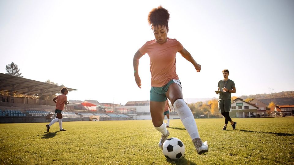 A female footballer running with the ball.