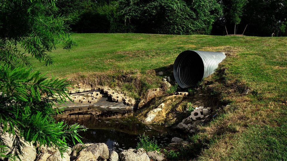 A pipe releasing water into a pond.