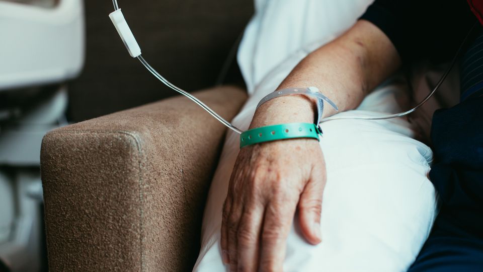 A close up of a patients hand hooked to a drip.
