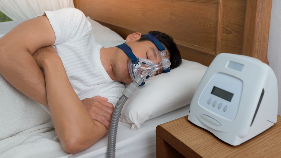 A person laying in bed wearing a CPAP mask for sleep apnea.