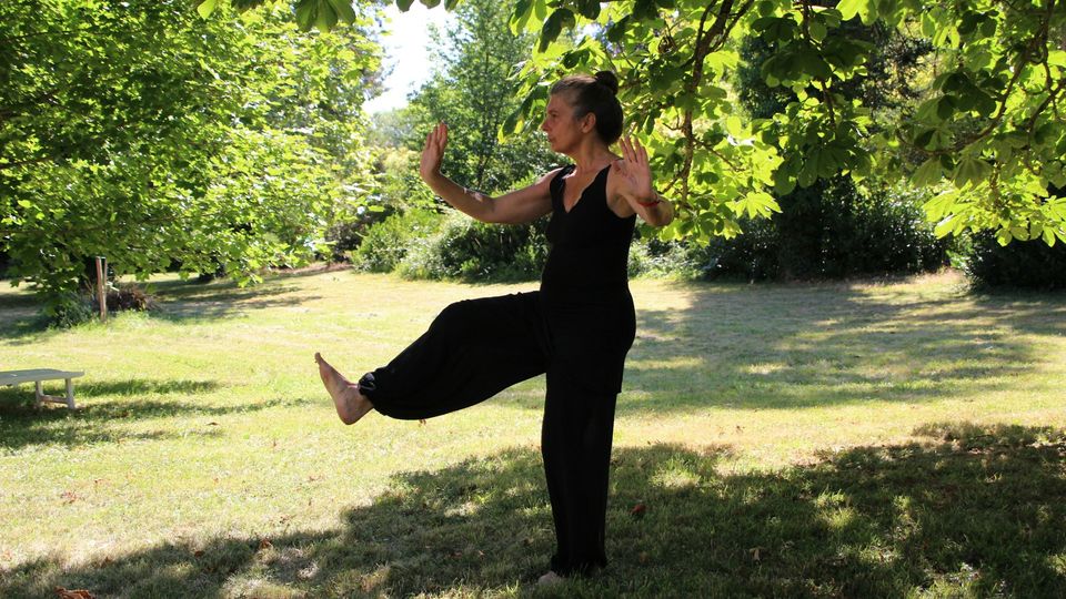 A woman performs Tai Chi in a park.
