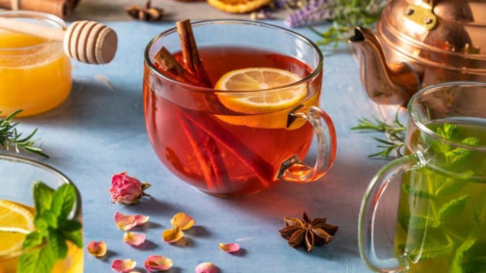 Black tea red tea and mint tea with copper teapot and herbs on blue wood background
