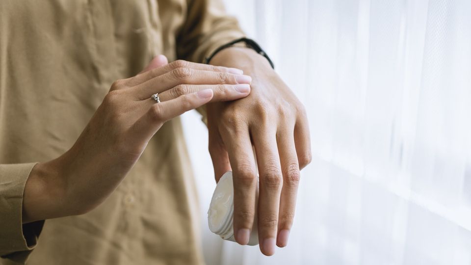 A person applies cream to their hands.