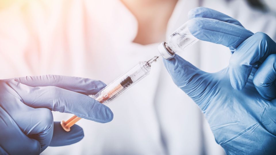 A person drawing up a vaccine in a syringe.