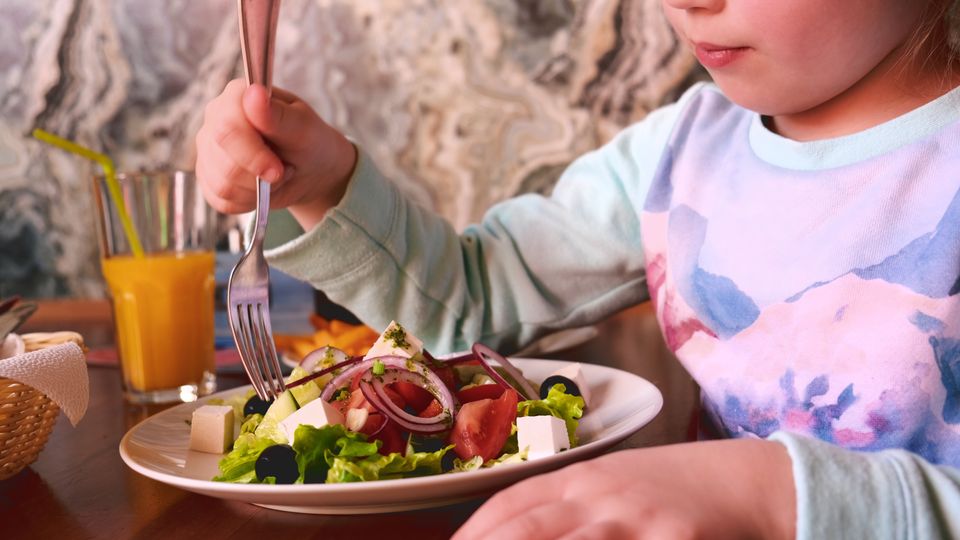A bowl of salad eaten by child.