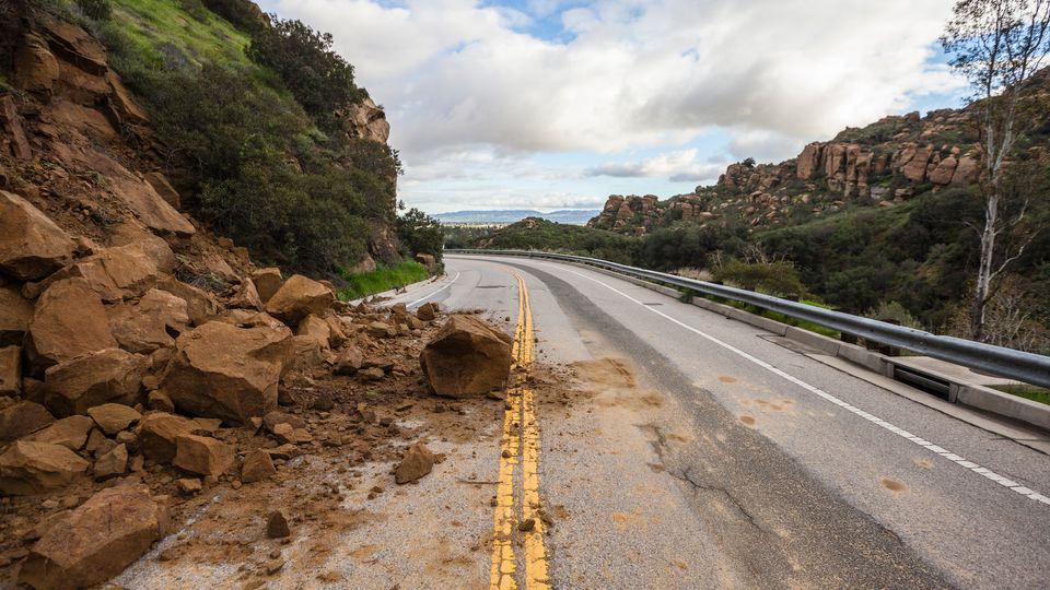 A rocky landslide covers half of a highway road