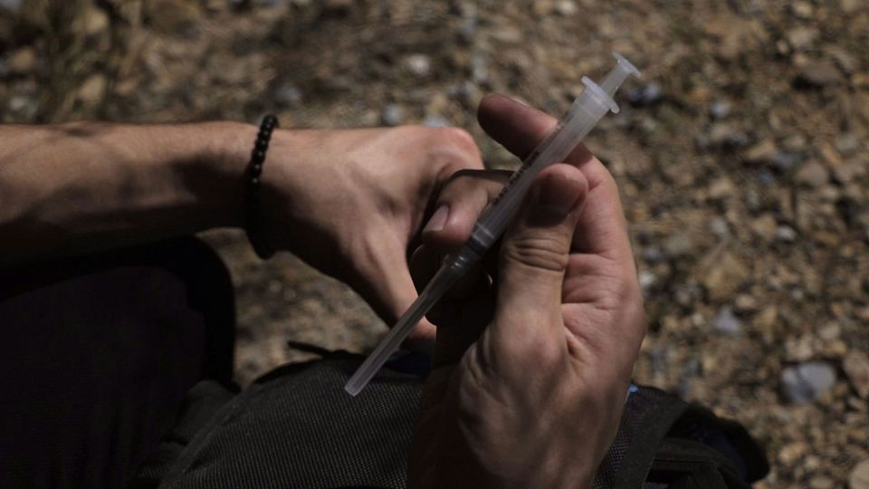 A person holds a capped syringe.