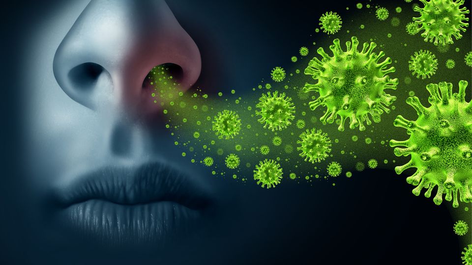 A close up of a human nose with virus particles coming out of it.