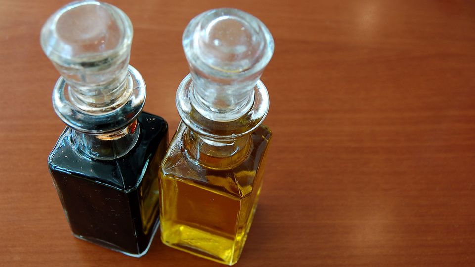 A bottle of vinegar next to a bottle of oil.