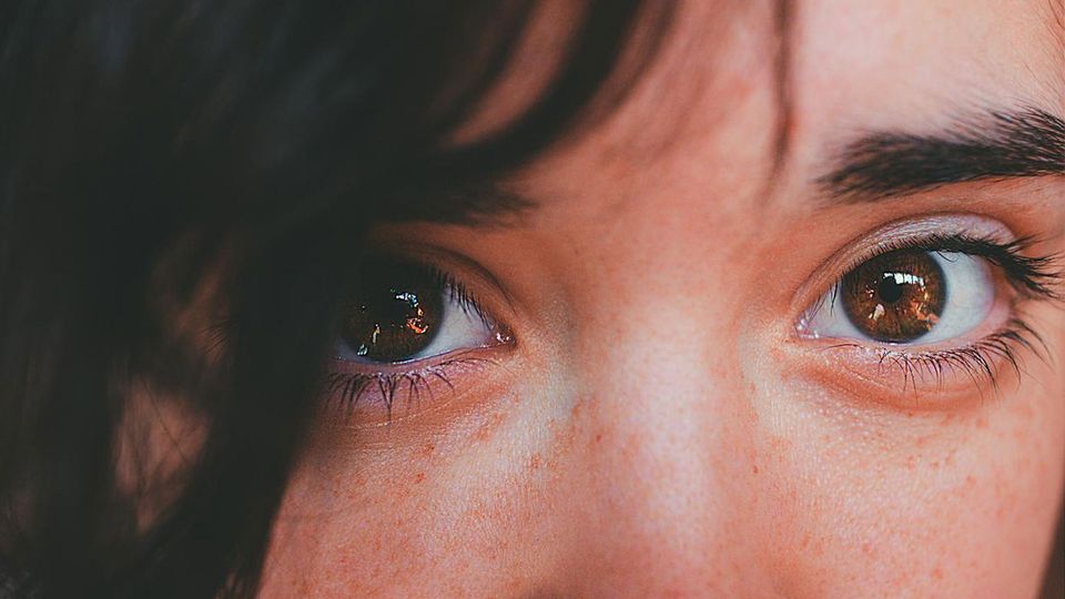 A woman with dark brown eyes looks into the camera.