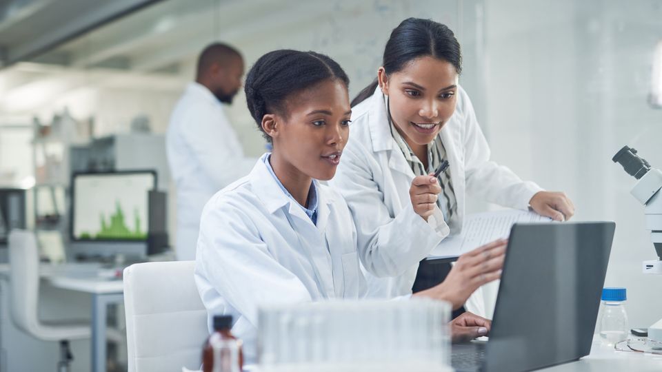 Two scientists looking at a laptop screen.