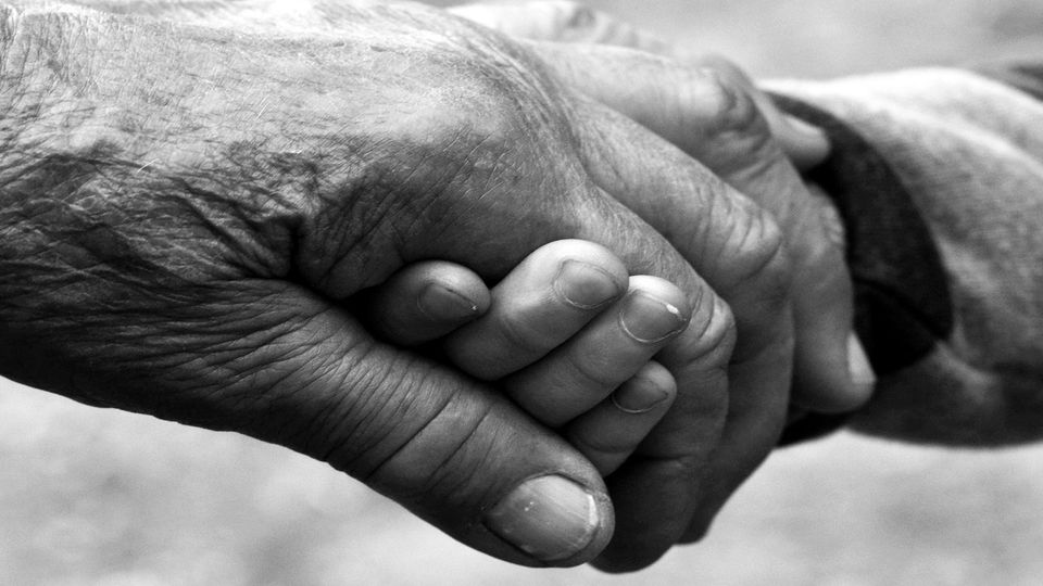 Older hand holding younger hand