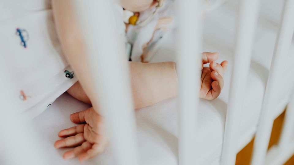 A close up of a baby's arms in a crib