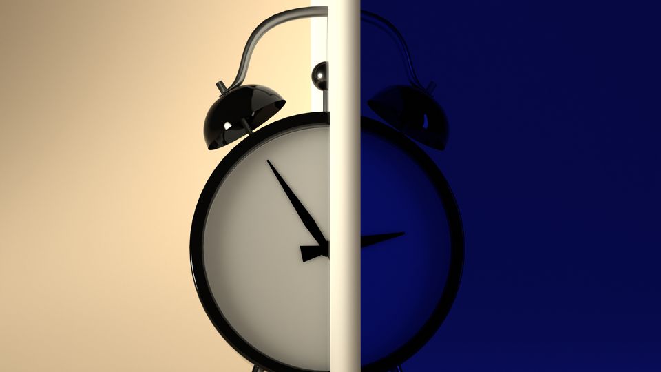 An alarm clock in front of a cream and blue background.