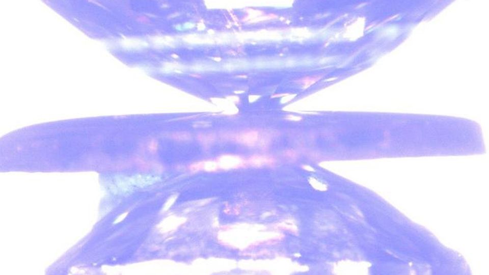 A laboratory image shows a rotational diamond anvil cell squeezing a sample within the gasket placed in the middle.