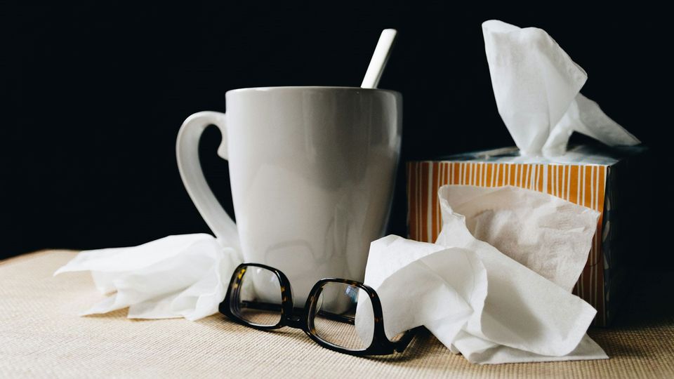 A mug with a box of tissues beside it.