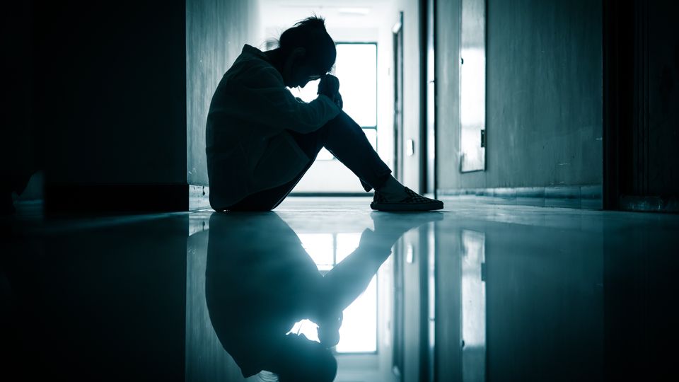 A woman sitting on the floor with her head in her hands.
