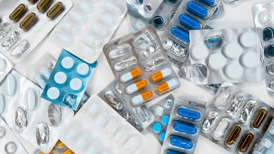 Pills of different sizes, shapes and colors in half-empty blister packs.