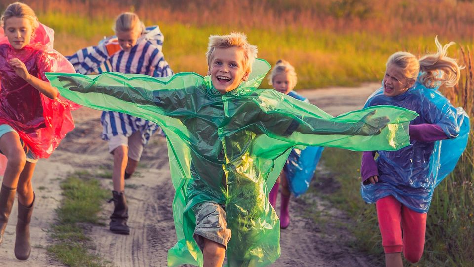 A group of children running in waterproof coats.