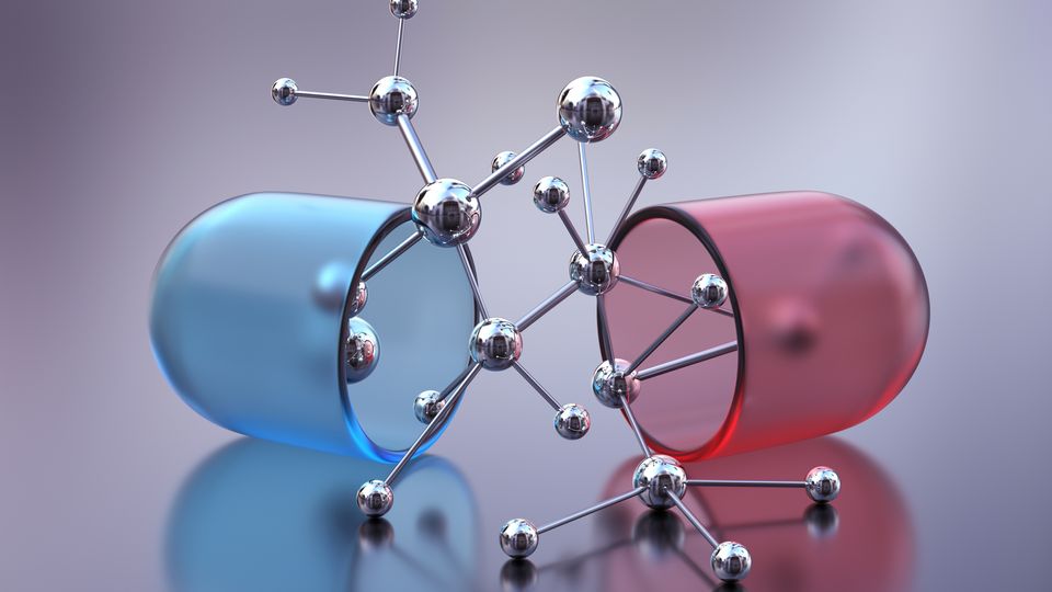 A drug capsule split in two with molecules in the middle.