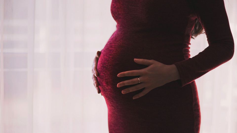 A pregnant person holds their baby bump.
