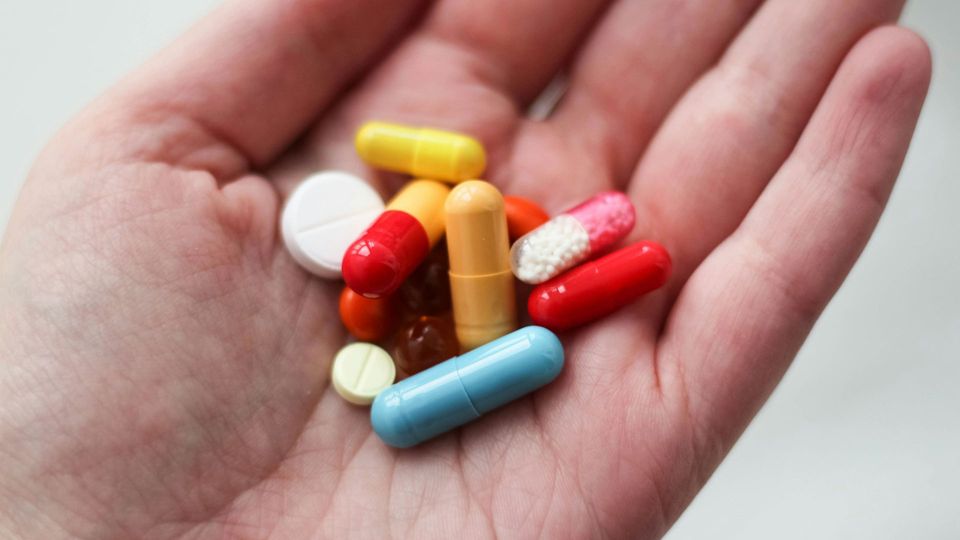 A handful of pills of different sizes, shapes and colors.