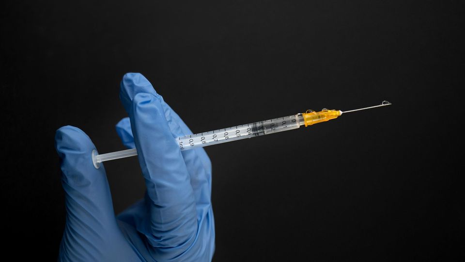 A gloved hand holds a syringe.