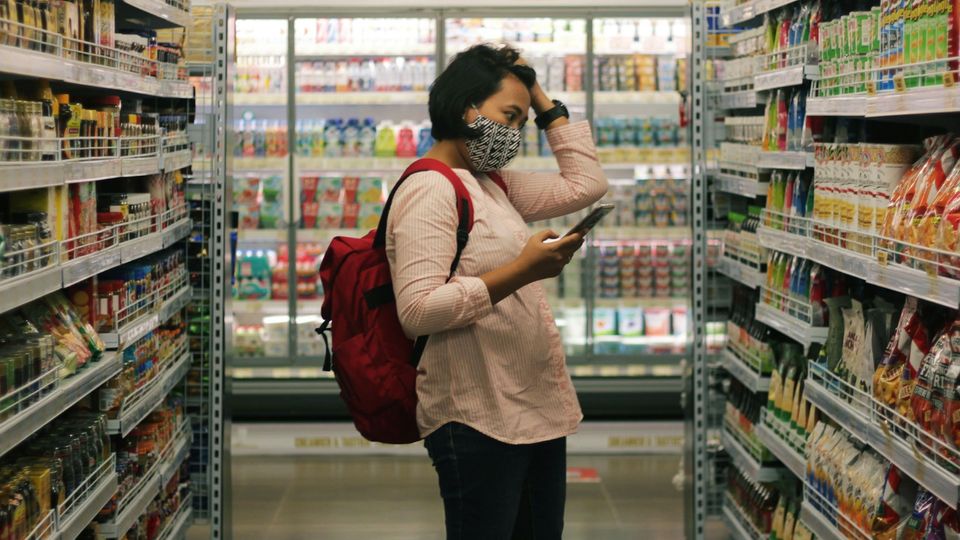 A person holding a phone looks at the options in a supermarket crisp aisle.