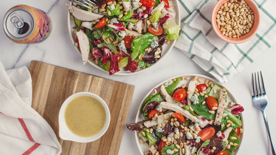 Two plates of chicken salad with pine nuts.