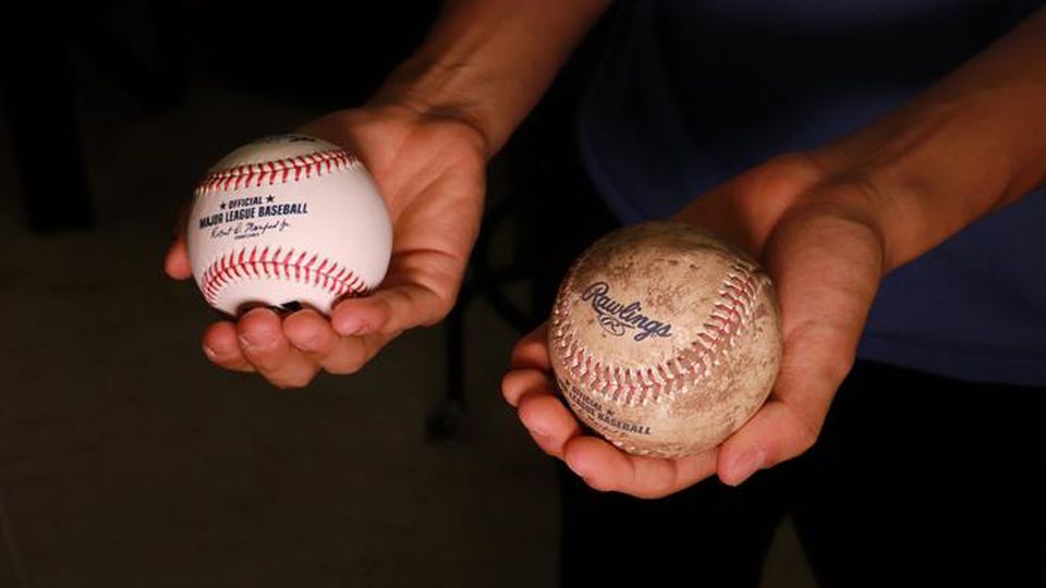 Two baseball balls held out, one covered in mud and the other clean.