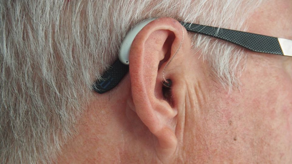 A close of of someone's ear who is wearing a hearing aid.