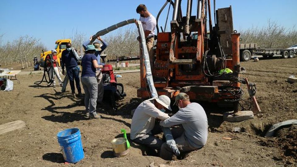 UC Davis researchers insert a device that continuously collects water samples underground, providing real-time data on nitrate contaminant movement.