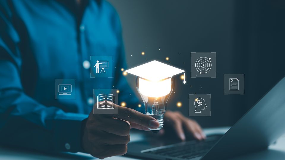 Person holding a lightbulb with a graduation cap, symbolizing innovative learning and digital education concepts.