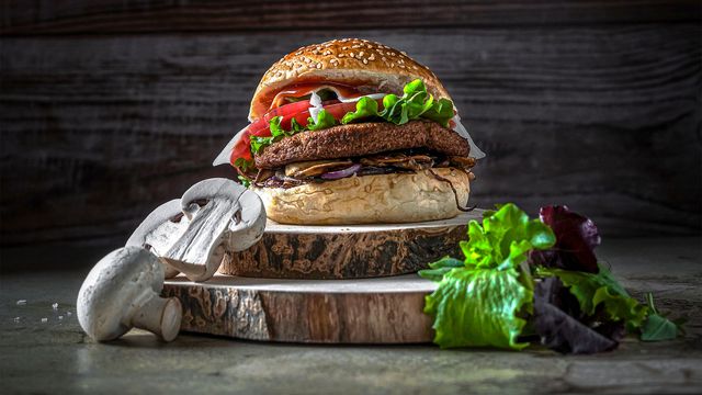 A burger with mushrooms on the side.