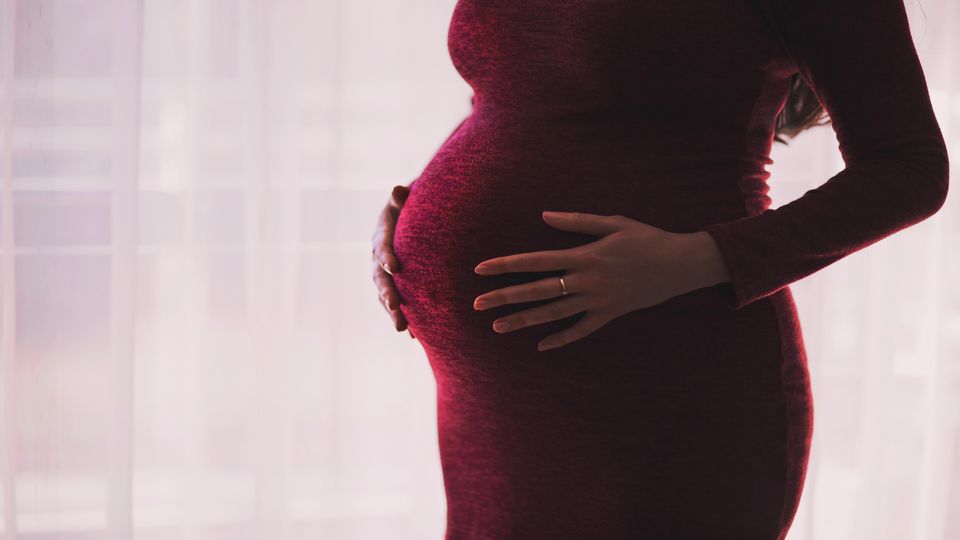 A pregnant woman holding her bump.