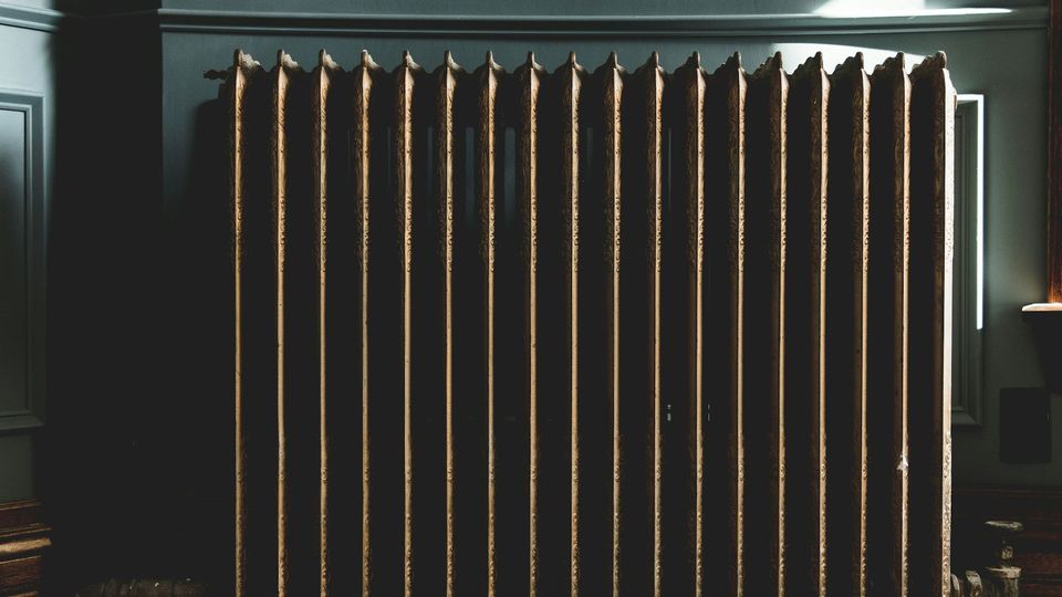 A radiator against a dark green wall.