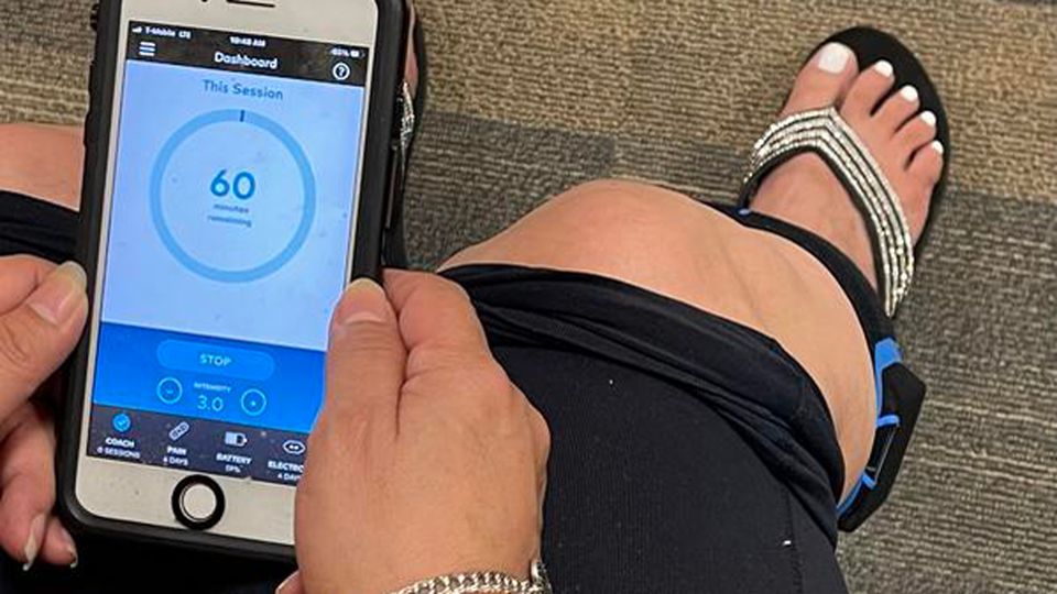 A woman wearing the Transcutaneous Electrical Nerve Stimulation (TENS) device around her leg.