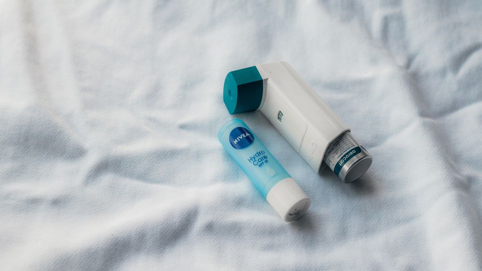 An asthma pump next to a lip balm tube.