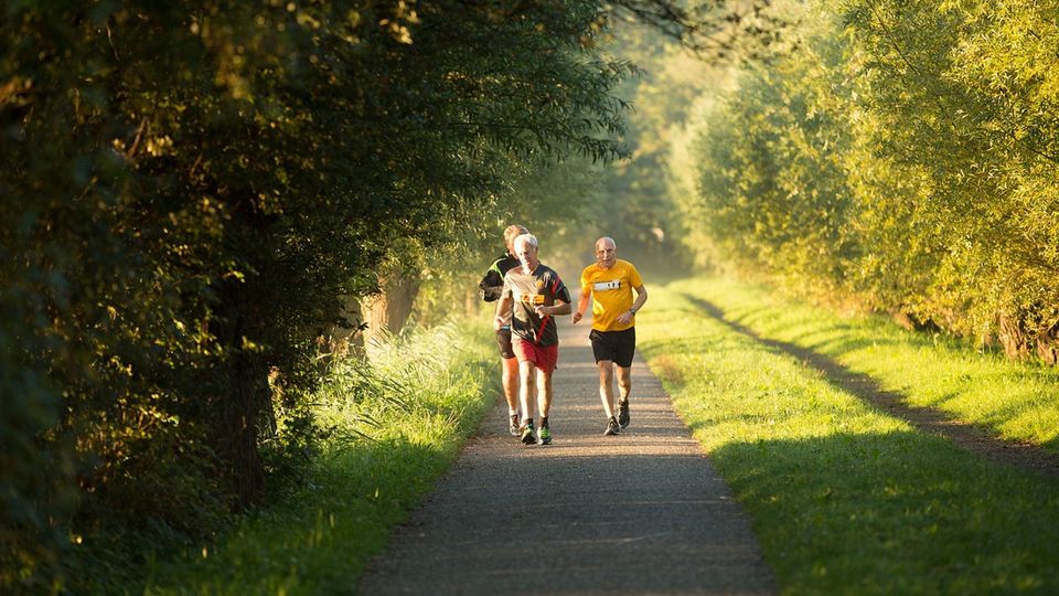Three men running along a path in countryside