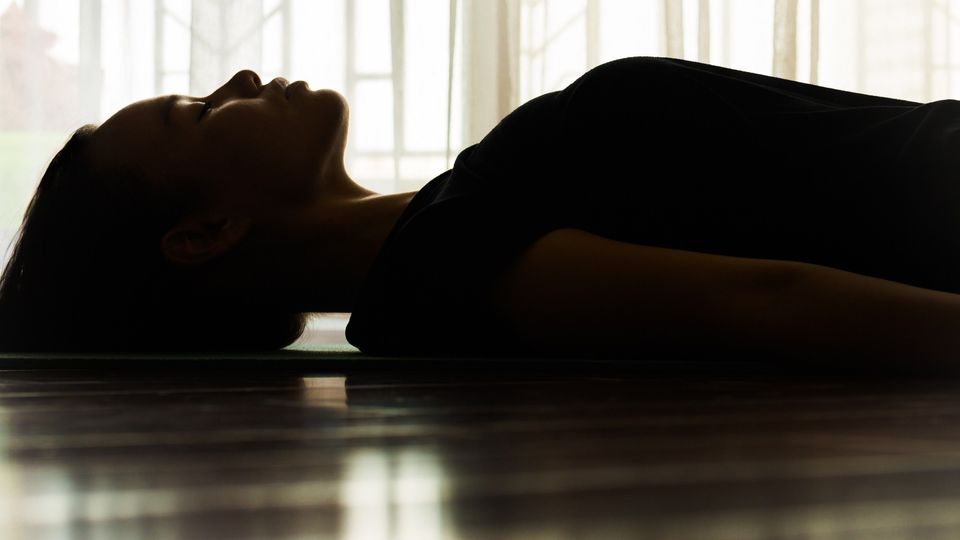 A woman laying on the floor with her eyes shut.
