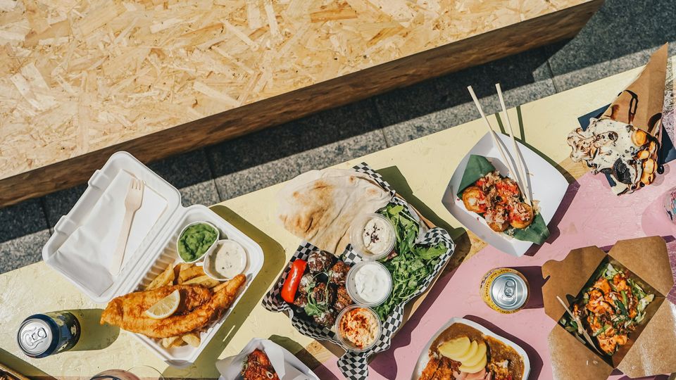 An aerial photo of a table covered with various takeaway foods in packaging.