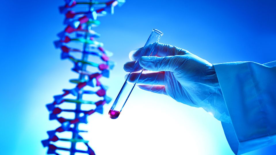 A researcher holds a glass vial containing pink liquid, with a DNA helix in the background.