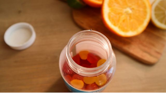 A jar of vitamin supplements next to some orange slices
