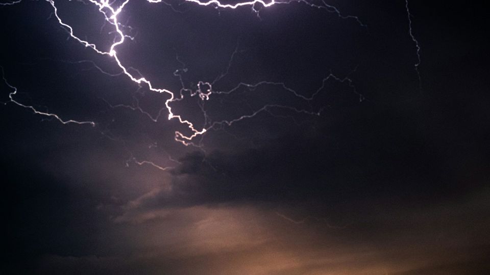 Lightning flashes against a dark, cloudy sky.