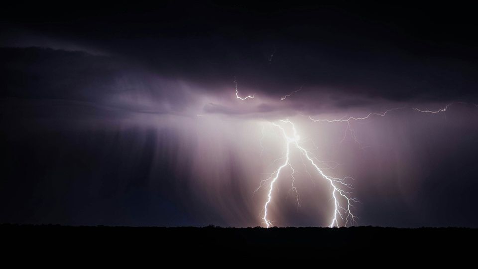 A lightning bolt from a dark cloudy sky hits the ground.