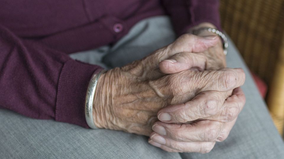 Older individuals hands clasped together