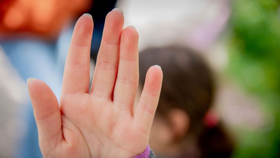 Child holding hand up to the camera as to indicate "stop".