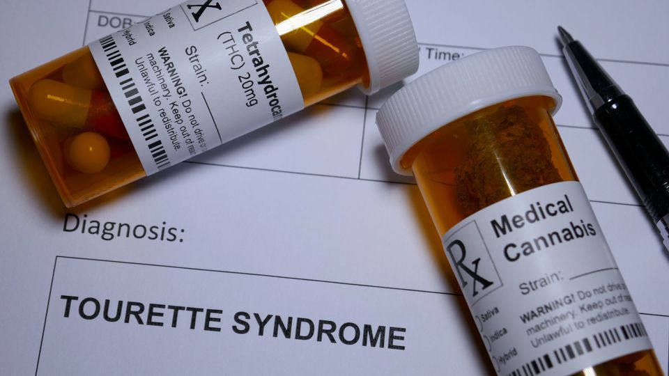 Prescription bottles labeled THC and medical cannabis placed on a diagnosis form for Tourette syndrome.