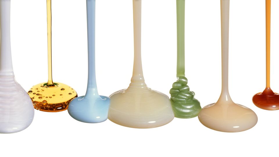 Various colored and textured fluids flowing down from above to create puddles.