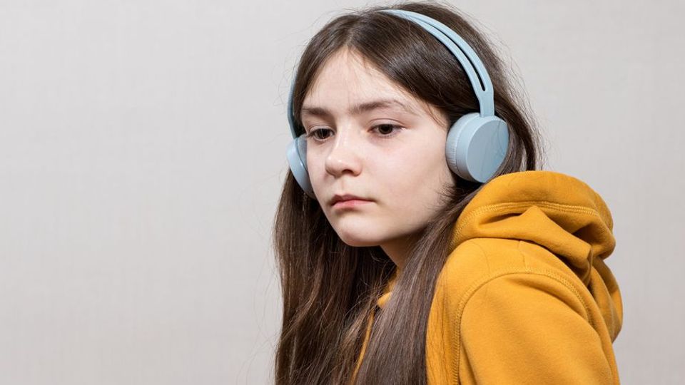A girl wearing headphones, representing someone with autism.